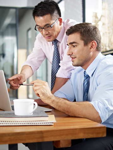 asian and caucasian businessmen working together in office