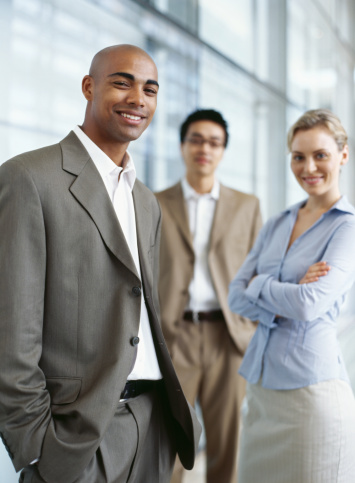 portrait of two businessmen and a businesswoman standing in an office